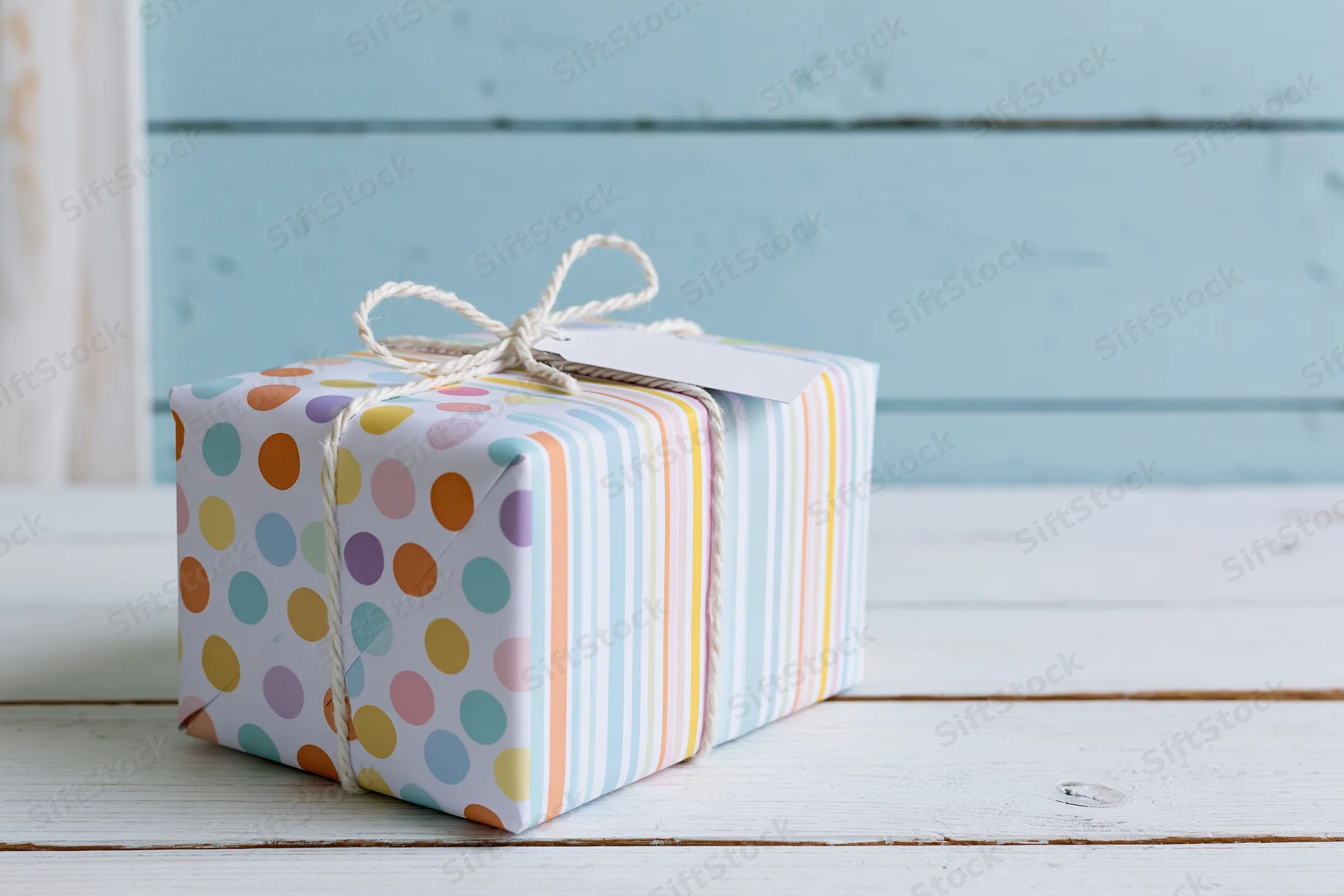 Wrapped gift box with polka dots and stripes on a white wooden surface