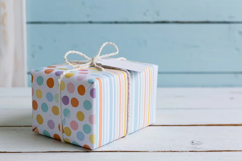 Wrapped gift box with polka dots and stripes on a white wooden surface