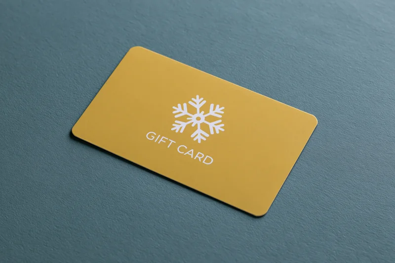 Yellow gift card with snowflake design lying flat on textured teal surface