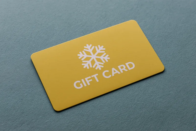 Yellow gift card with snowflake design lying flat on textured teal surface