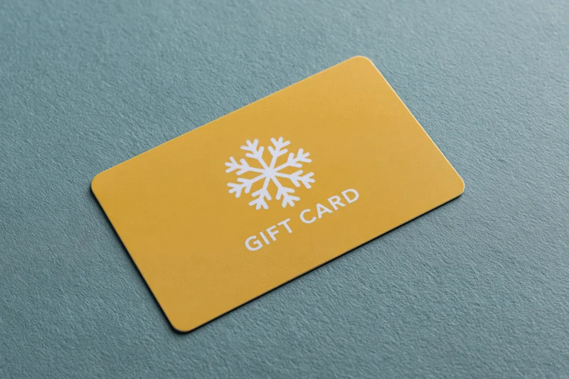 Yellow gift card with snowflake design lying flat on textured teal surface