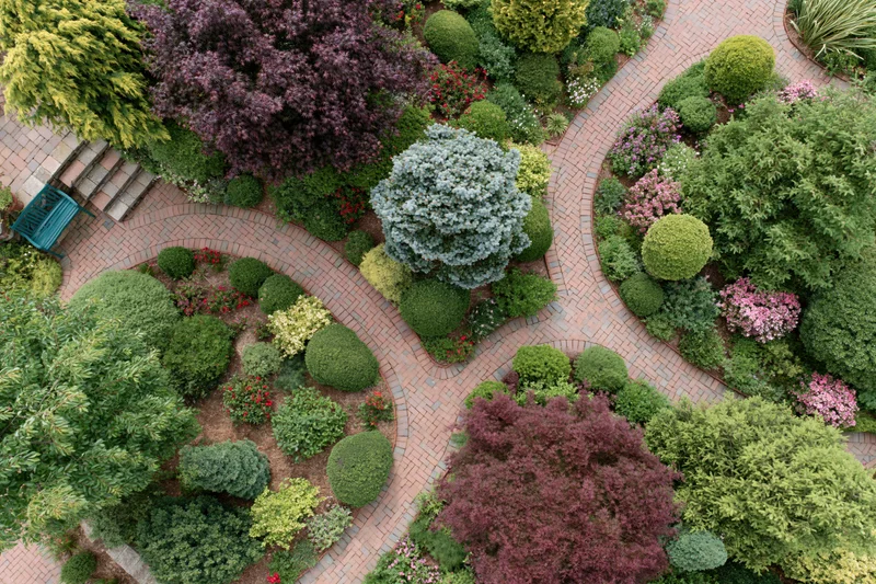 Aerial top-down view of a landscaped residential garden with curved brick pathways and ornamental shrubs and flowers