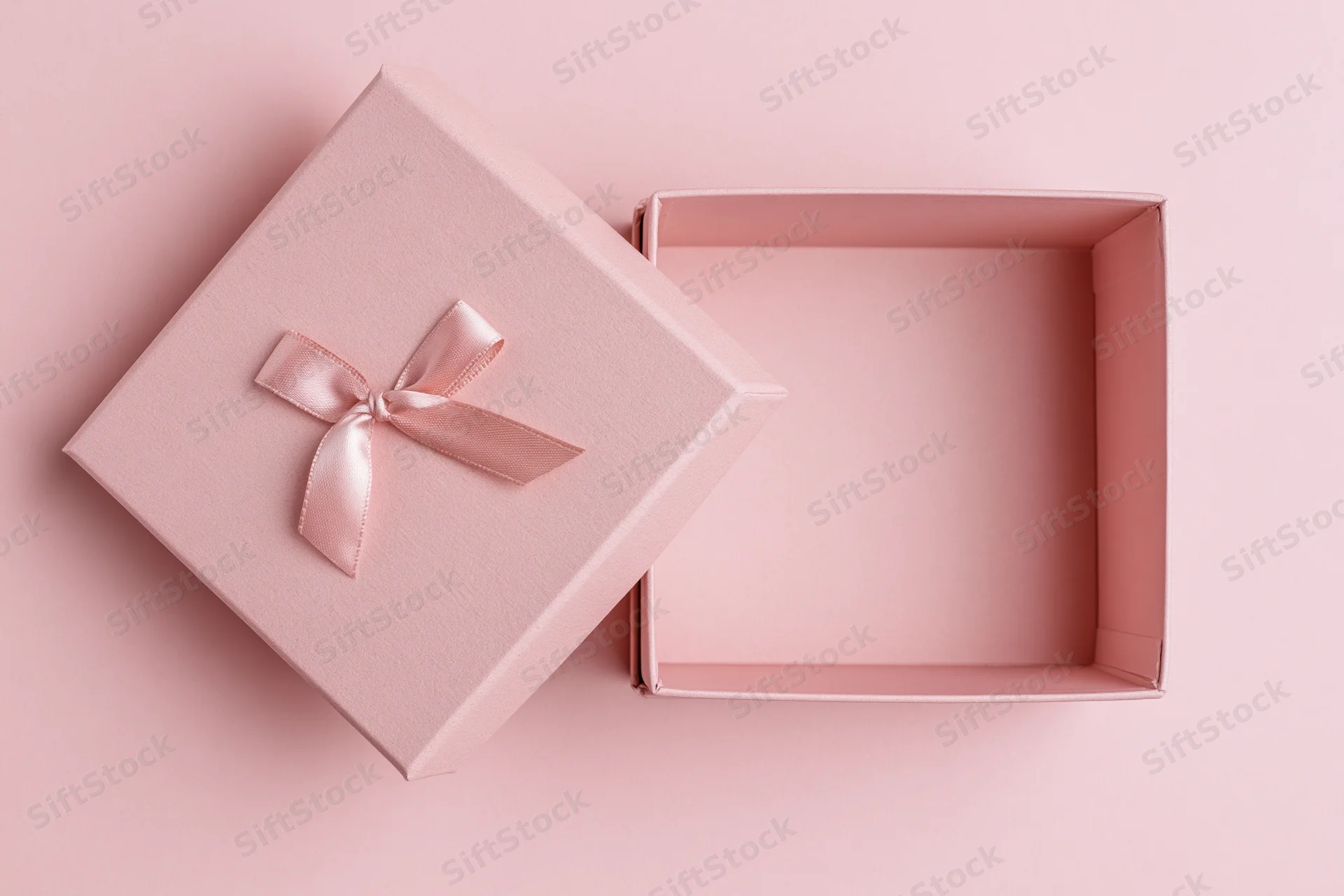 Open pink gift box with lid and ribbon on matching background
