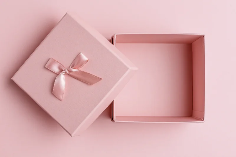 Open pink gift box with lid and ribbon on matching background