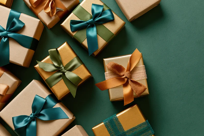 Assorted wrapped gift boxes scattered on a deep green surface with copyspace