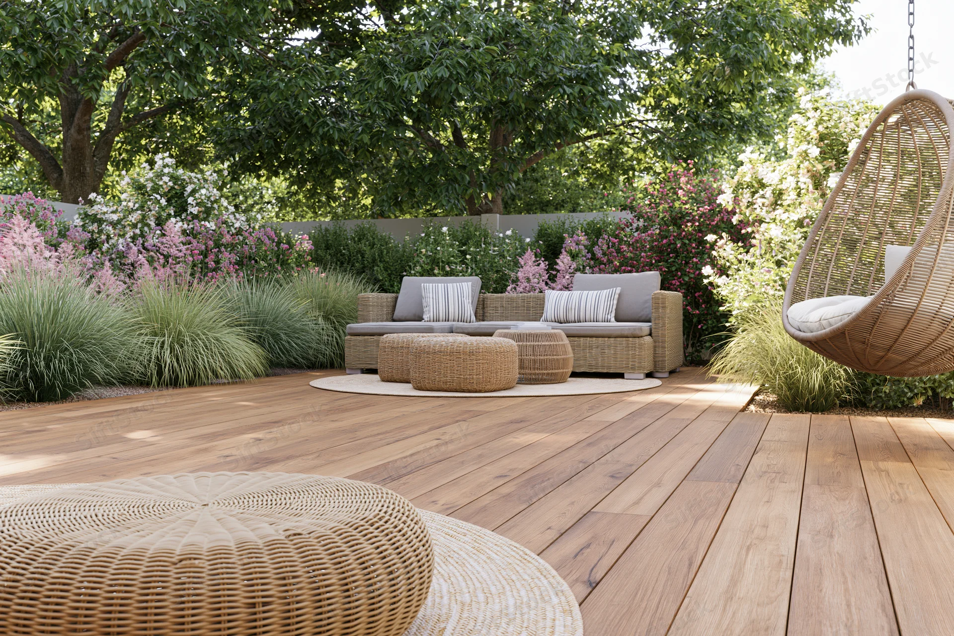 Wooden deck with rattan lounge furniture and hanging swing surrounded by flowering shrubs and trees