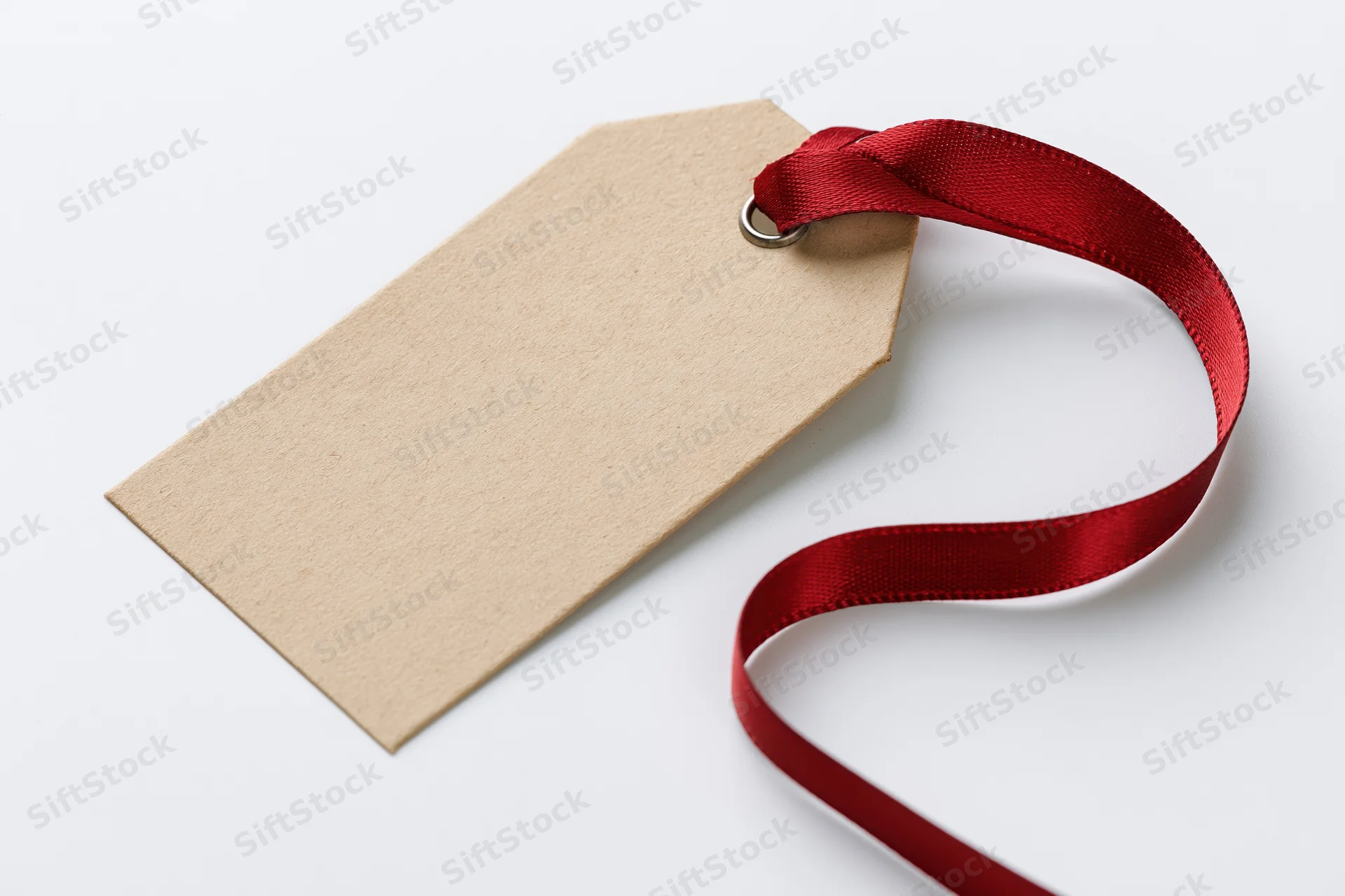 Blank kraft paper gift tag with red satin ribbon on white background