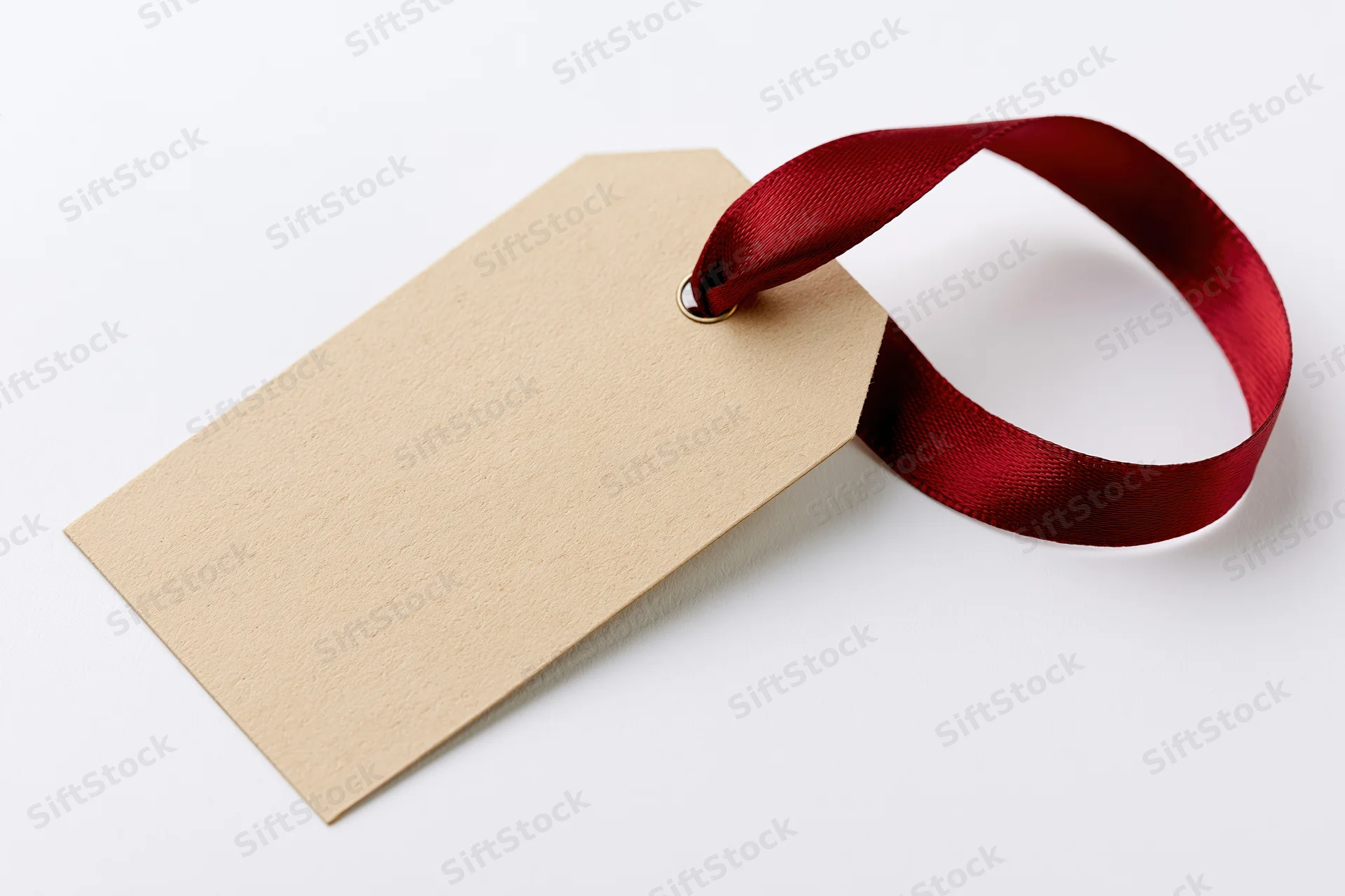 Blank kraft paper gift tag with red satin ribbon on white background