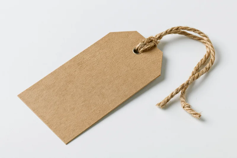 Blank kraft paper tag with twisted jute twine string on white background