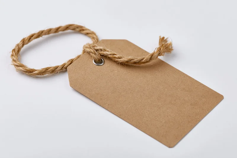Blank kraft paper tag with twisted jute twine string on white background