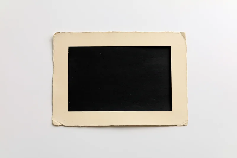 Vintage blank photo print with torn paper border lying flat on white surface