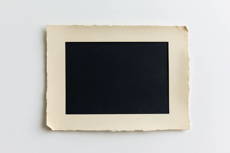 Vintage blank photo print with torn edges lying flat on white surface