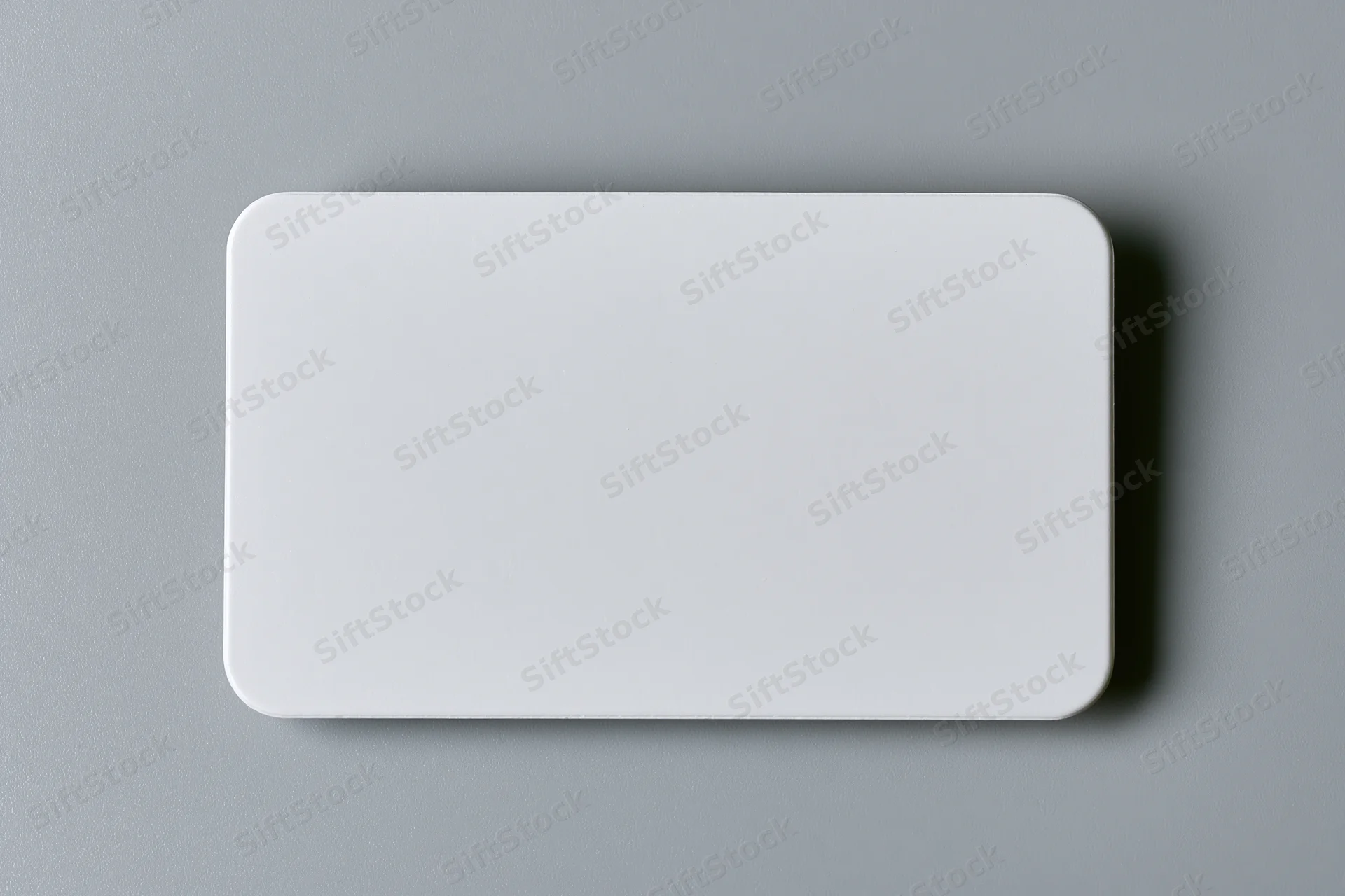 Blank white business card with rounded corners lying flat on gray surface