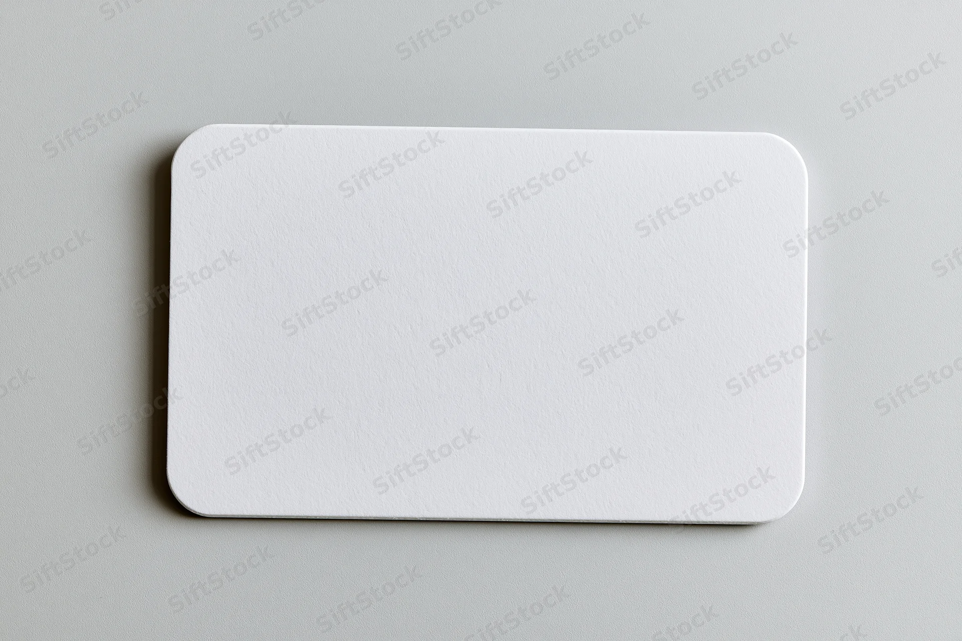 Blank white business card with rounded corners lying flat on gray surface