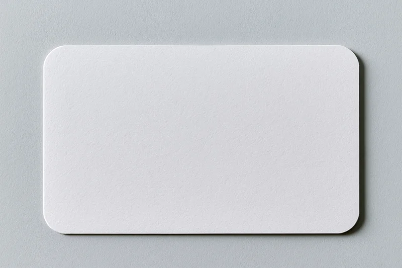 Blank white business card with rounded corners lying flat on gray surface