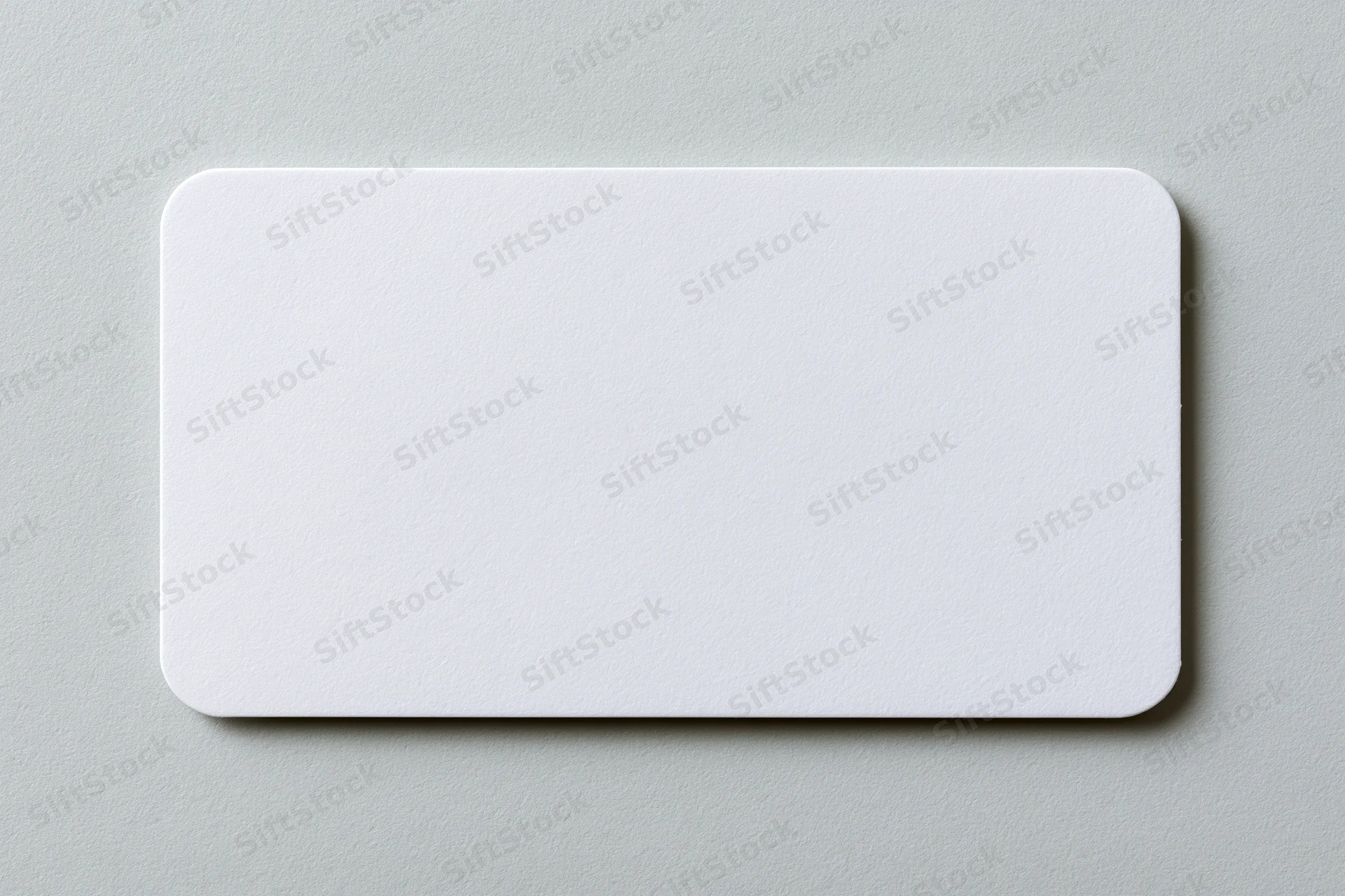 Blank white business card with rounded corners lying flat on a gray surface