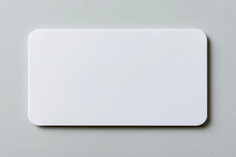 Blank white business card with rounded corners lying flat on a gray surface