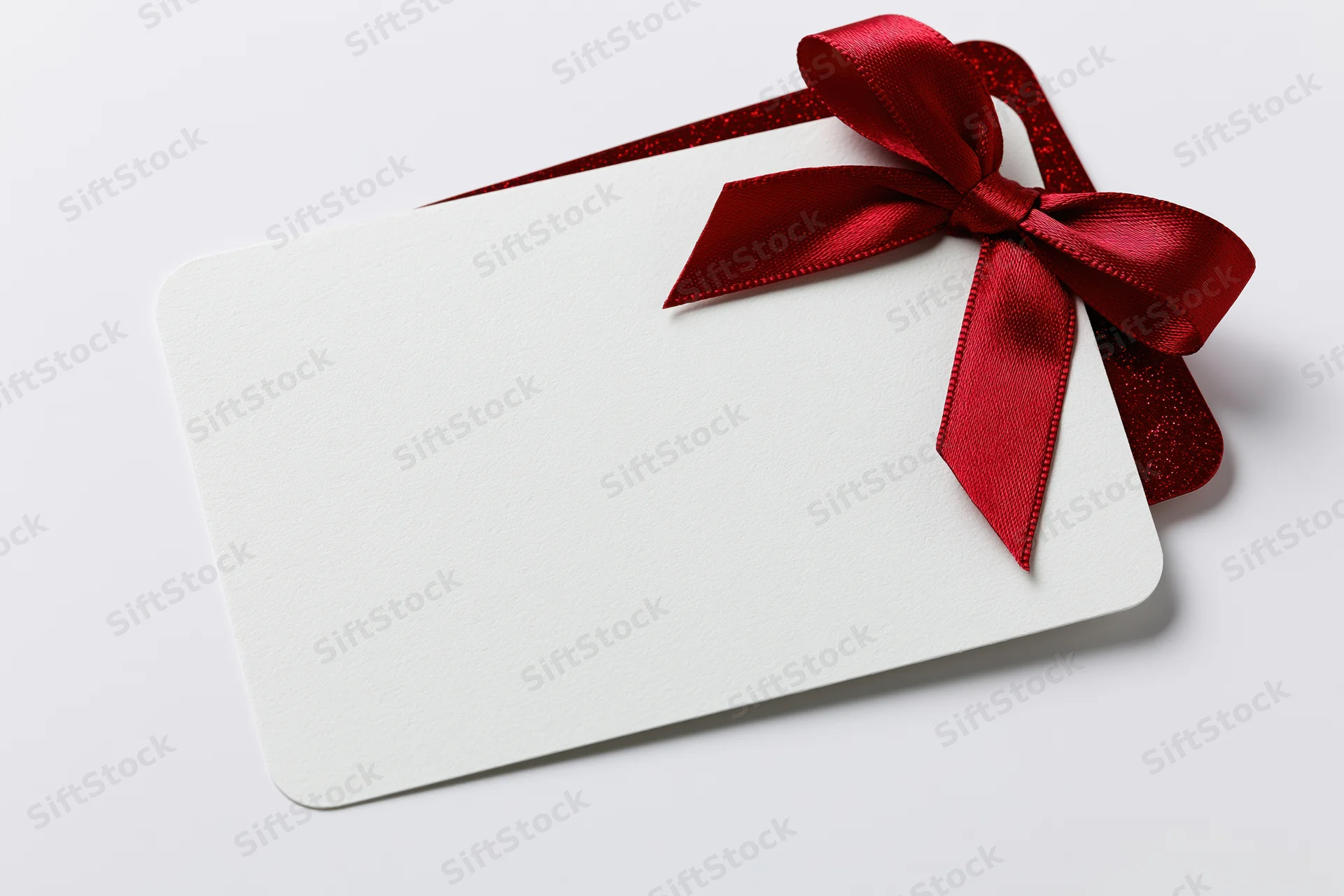 Blank white gift card with red ribbon bow on white background