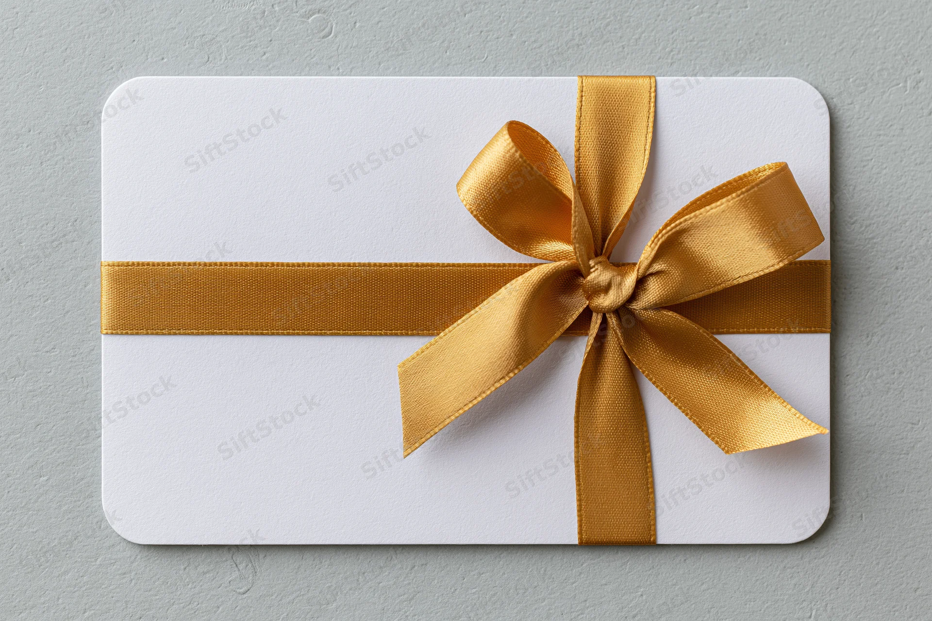 White gift card with gold ribbon bow on textured surface