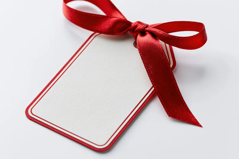 Blank white gift tag with red border and red ribbon bow on white background