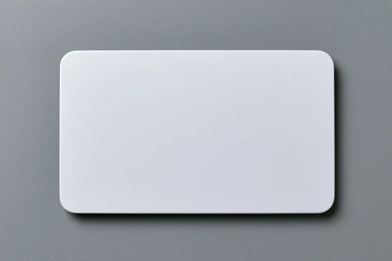 Blank white plastic card with rounded corners lying flat on gray surface