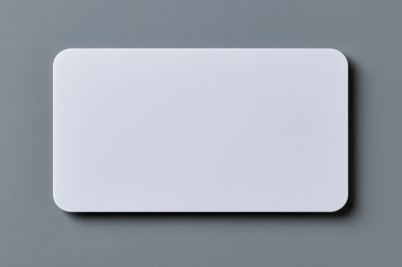 Blank white plastic card with rounded corners lying flat on gray surface