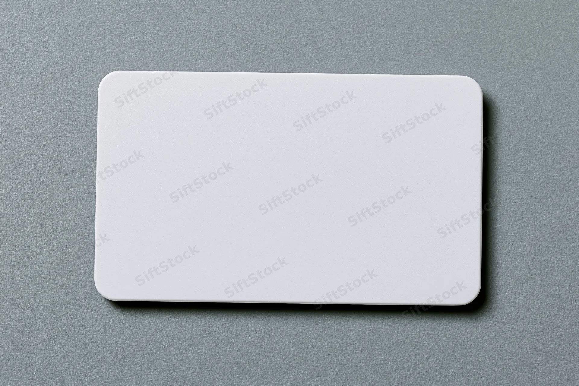 Blank white plastic card with rounded corners lying flat on a gray textured surface