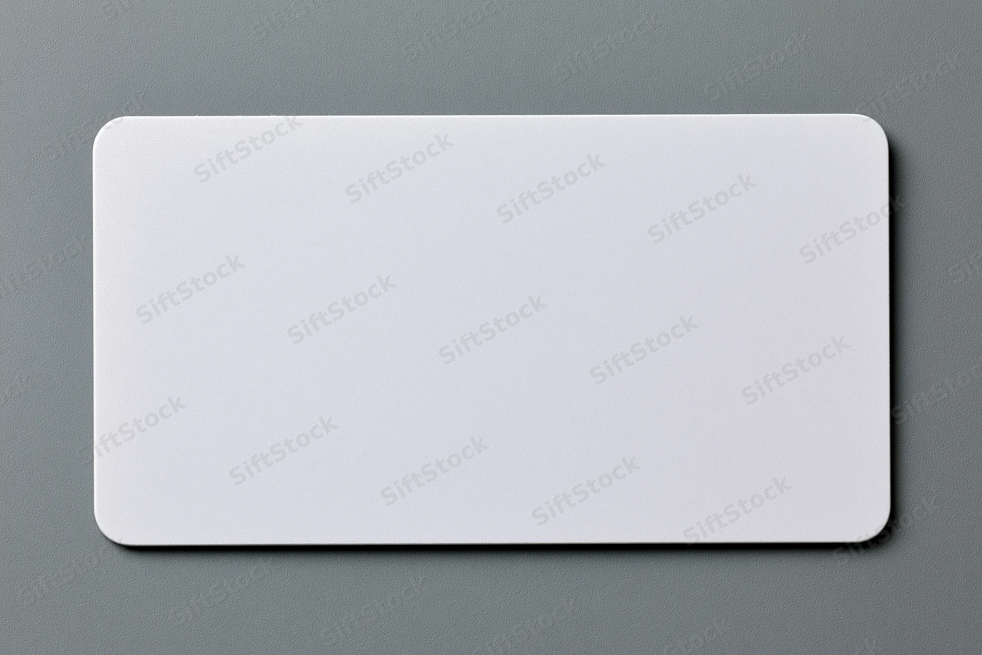 Blank white plastic card with rounded corners lying flat on gray textured surface
