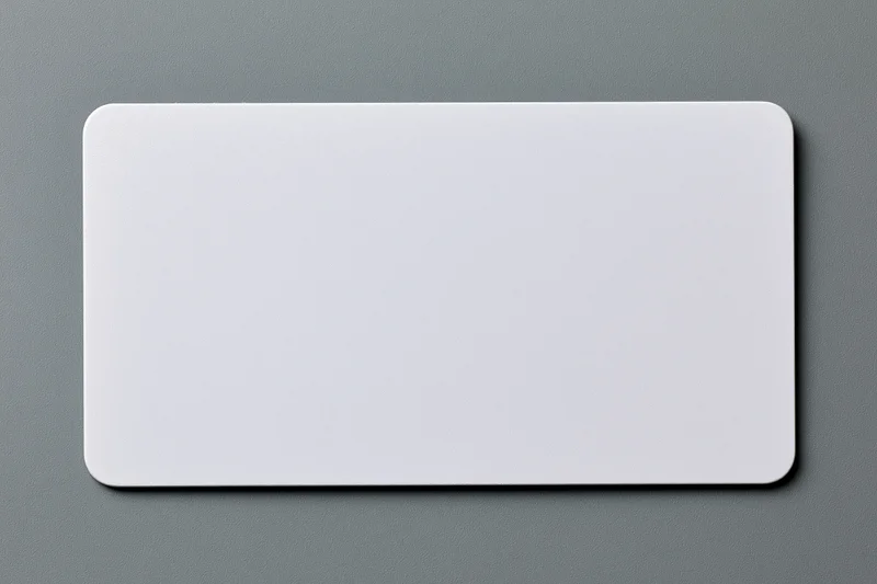 Blank white plastic card with rounded corners lying flat on gray textured surface