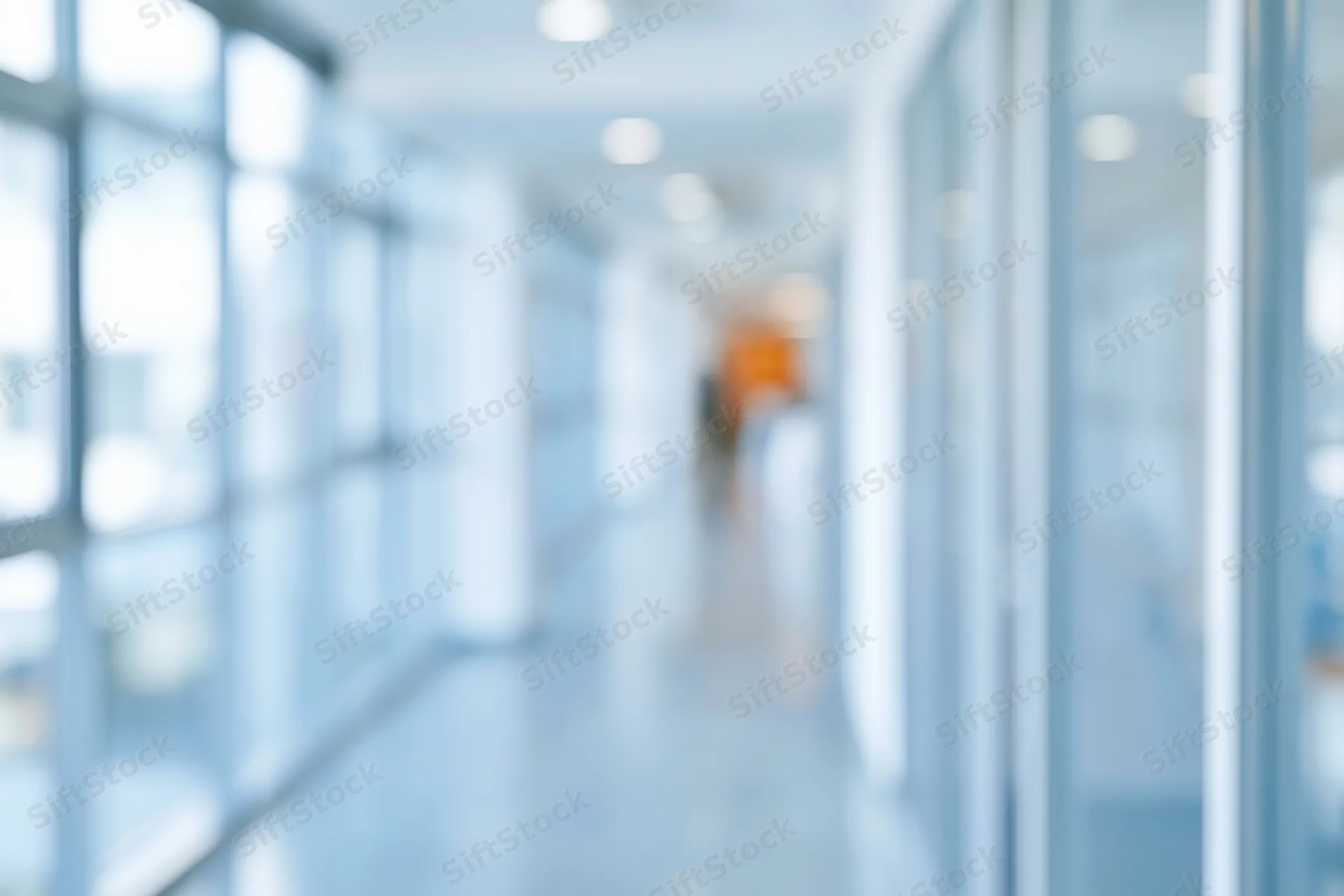 Blurred view of a modern office corridor with glass walls and bright lighting