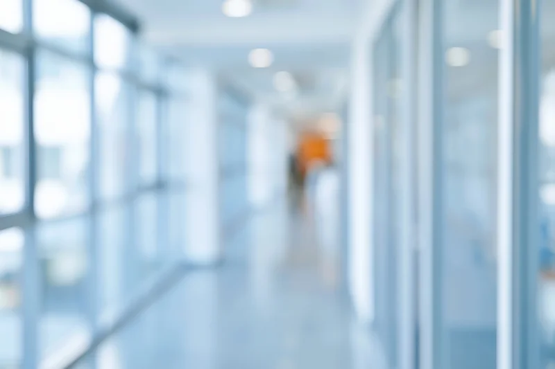 Blurred view of a modern office corridor with glass walls and bright lighting