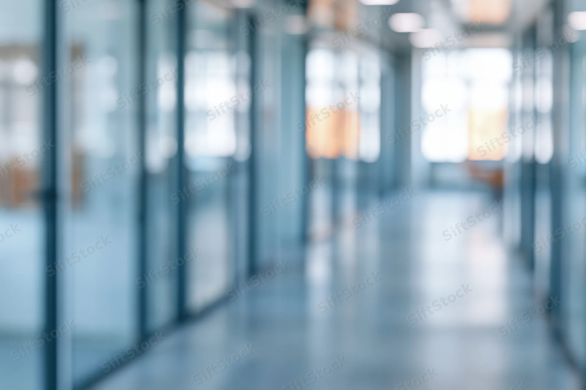 Blurred view of a modern office corridor with glass partitions and bright lighting