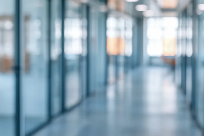 Blurred view of a modern office corridor with glass partitions and bright lighting