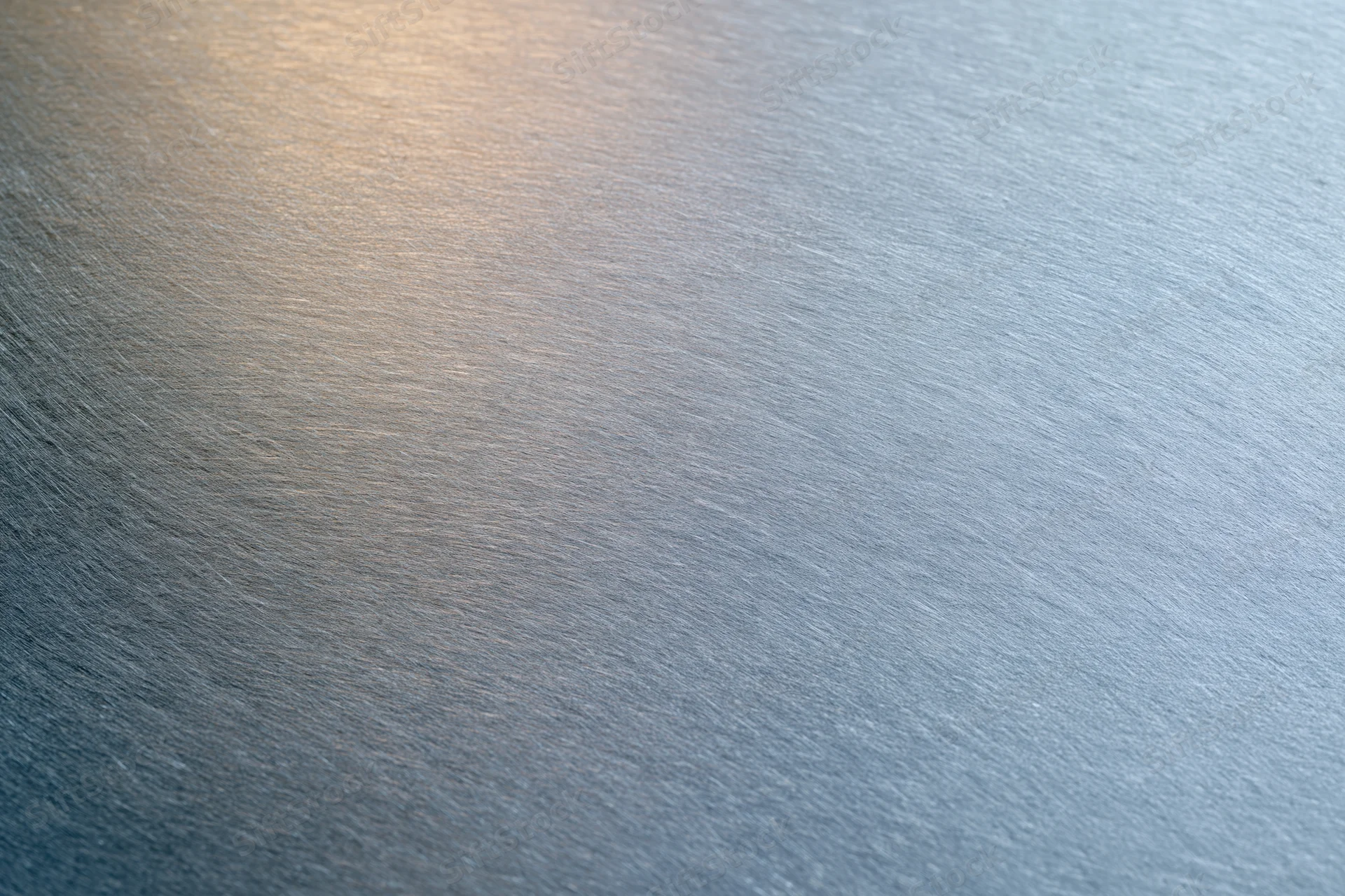 Close-up of brushed metal surface with soft reflected light