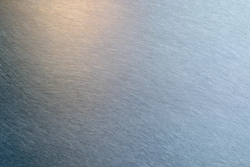 Close-up of brushed metal surface with soft reflected light