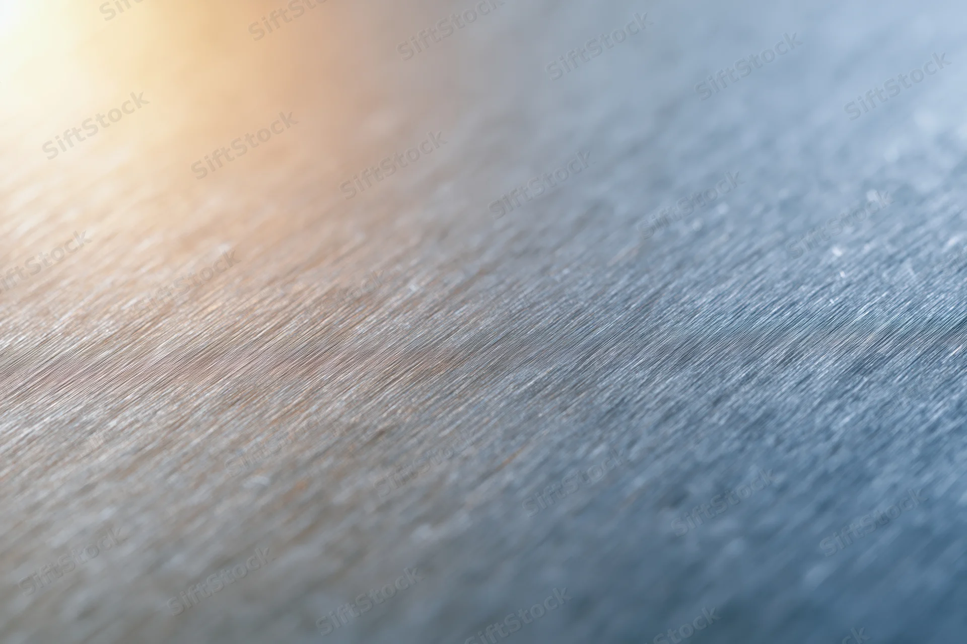 Close-up of brushed metal surface with soft light reflections and textured grain