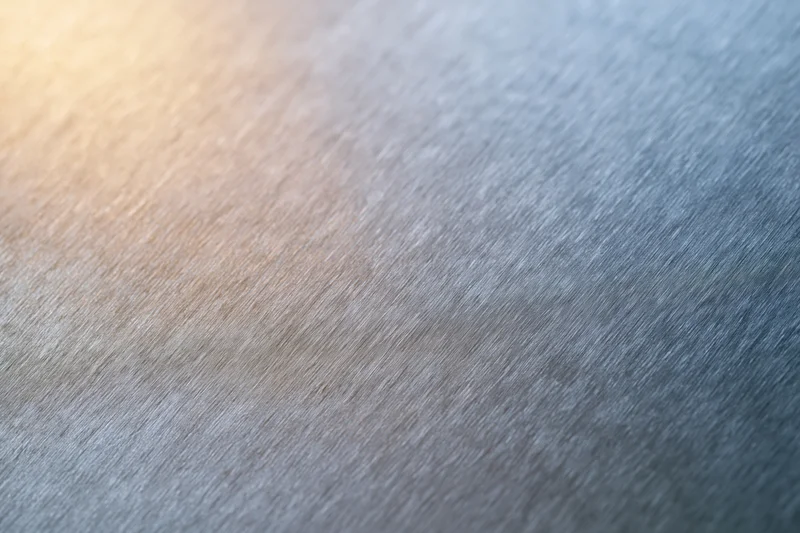 Close-up of brushed metal surface with soft light reflections and gradient tones