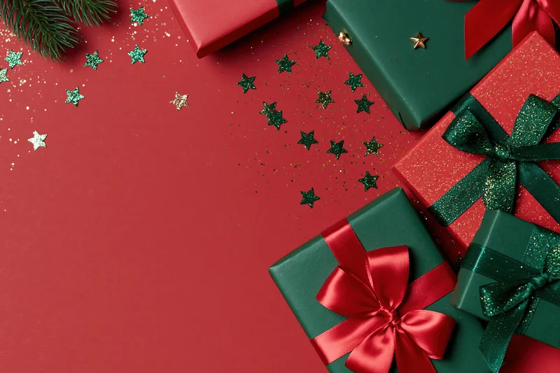 Christmas gift boxes wrapped in red and green paper with ribbons and stars on a red surface