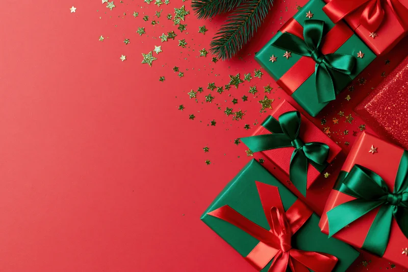 Christmas gift boxes wrapped in red and green paper with ribbons and pine branches on a red background