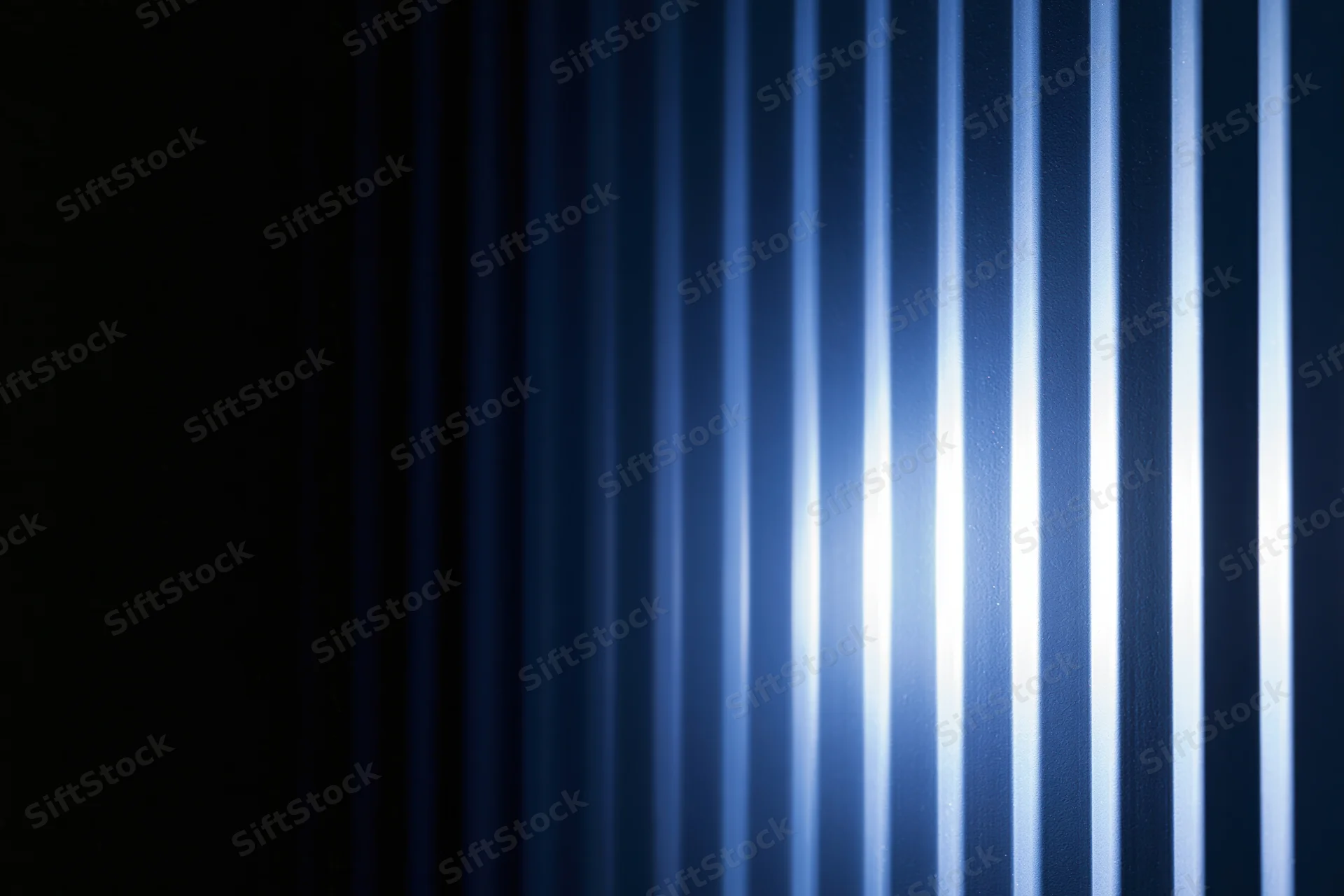 Vertical ridged panels illuminated with blue light creating striped texture and gradient glow