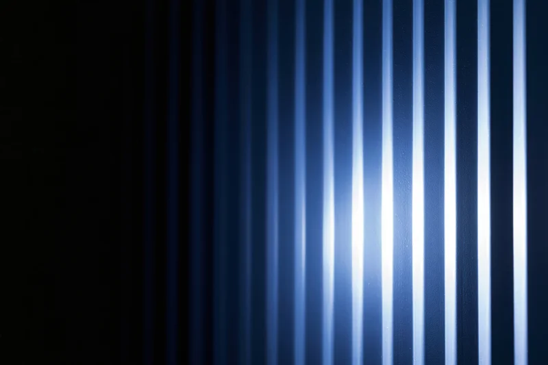 Vertical ridged panels illuminated with blue light creating striped texture and gradient glow