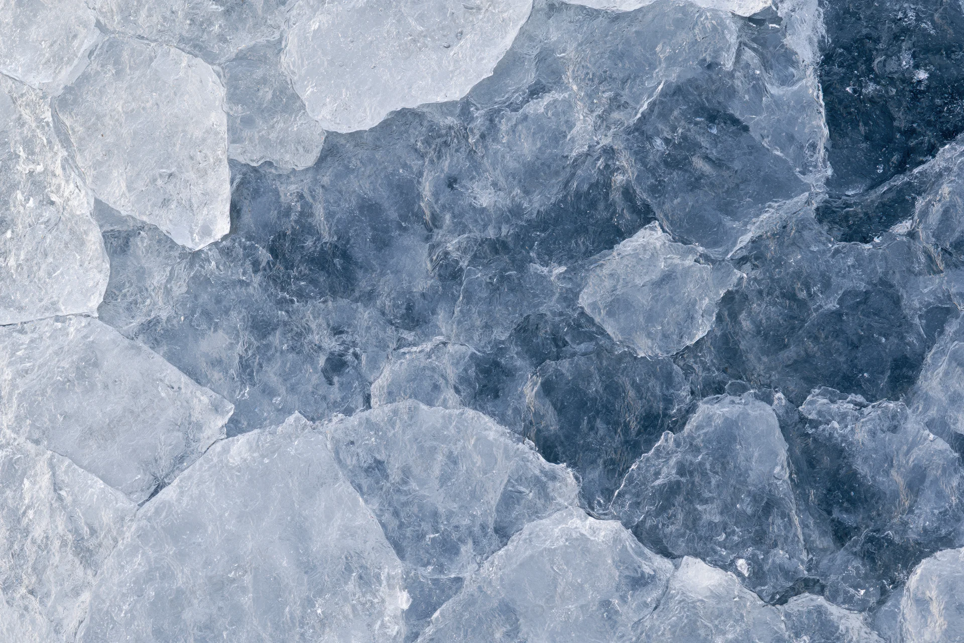 Close-up of fractured ice surface with blue and white shards forming a textured pattern
