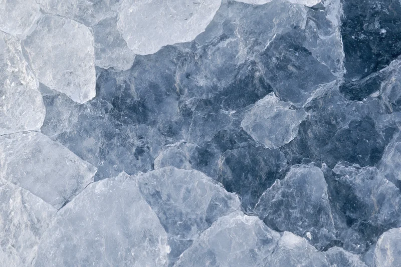Close-up of fractured ice surface with blue and white shards forming a textured pattern