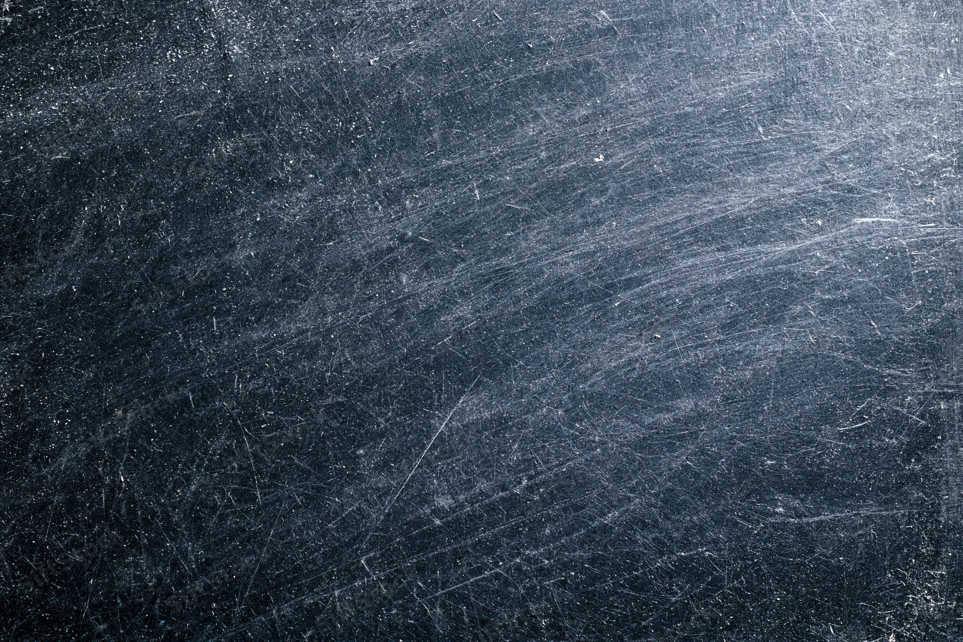 Close-up of a dark scratched metal surface with visible wear and texture
