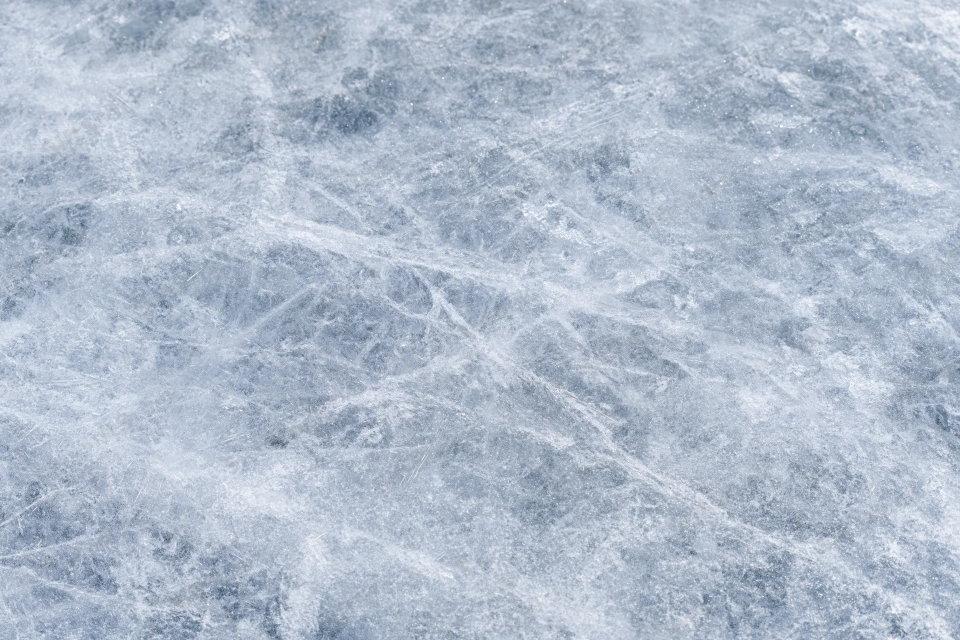 Close-up of a frozen ice surface with natural cracks and scratches, flat lay view