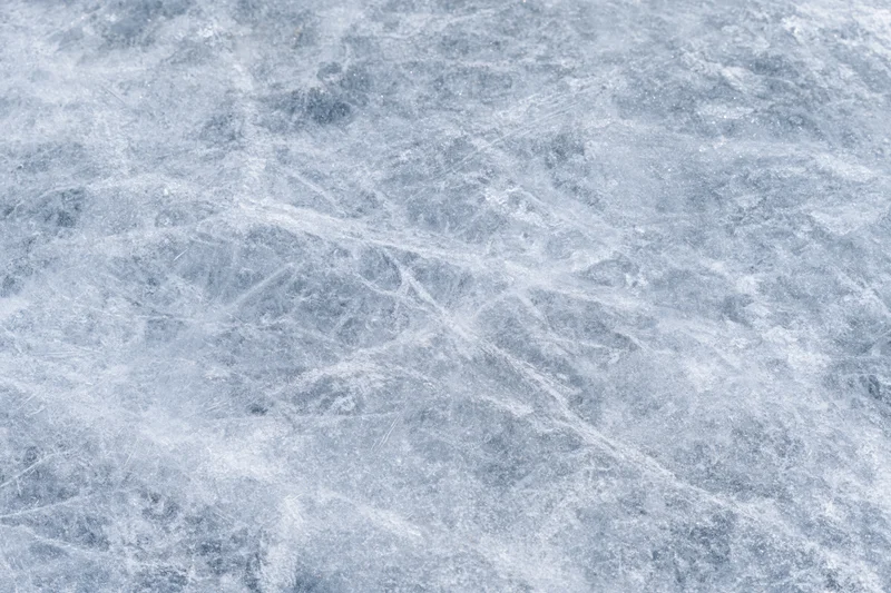Close-up of a frozen ice surface with natural cracks and scratches, flat lay view