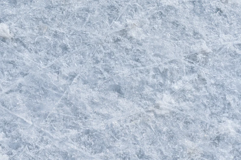 Close-up of a frozen ice surface with natural texture and frost patterns