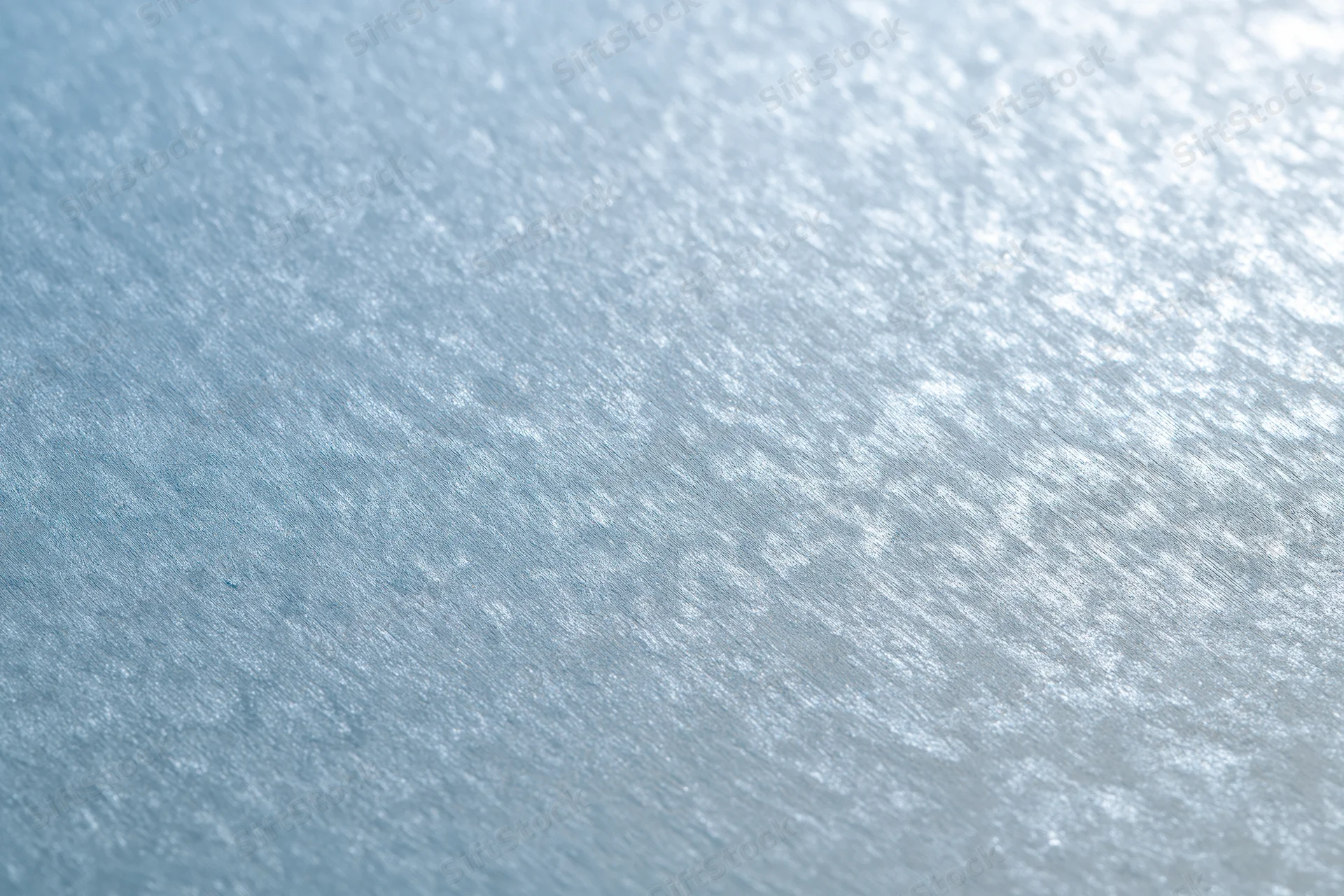 Close-up of frosted glass surface with brushed metallic texture and light reflections