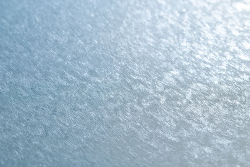 Close-up of frosted glass surface with brushed metallic texture and light reflections