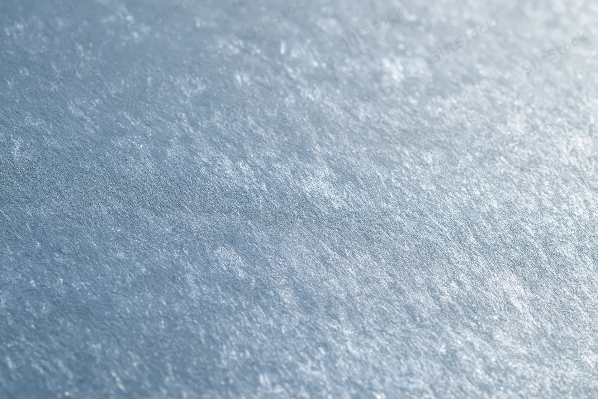 Close-up of frosted glass surface with brushed metallic texture and soft light reflections